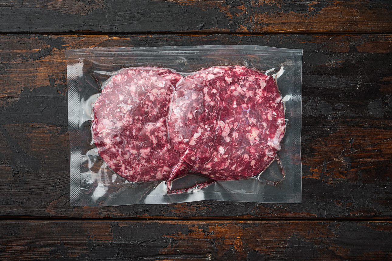 beef-patties-in-vacuum-packing-set-on-old-dark-wooden-table-background-top-view-flat-lay