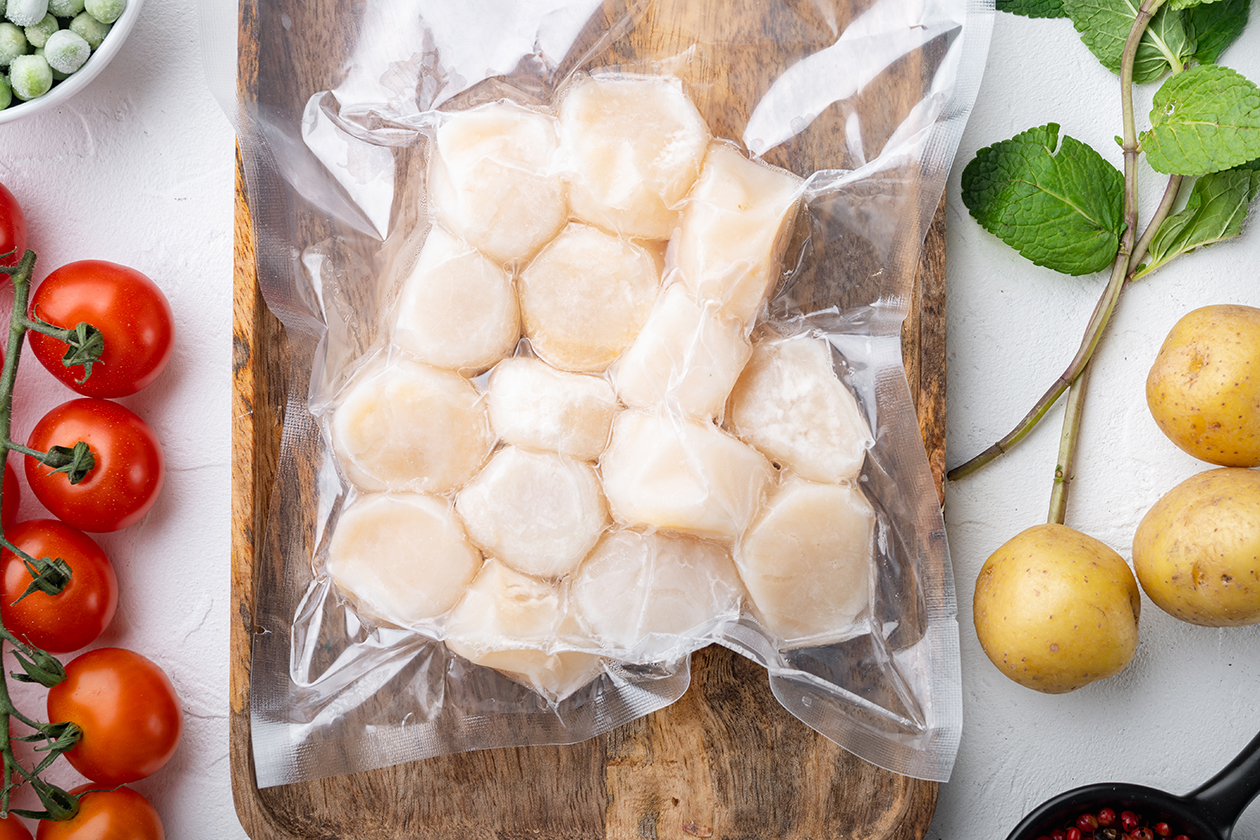 frozen-meat-scallops-in-vacuum-package-flat-lay-on-white-textured-table